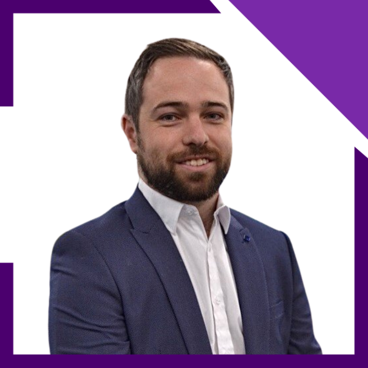 A man with a beard is wearing a blue suit and white shirt