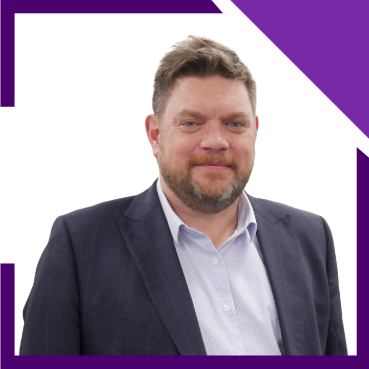 A man with a beard is wearing a suit and a white shirt.