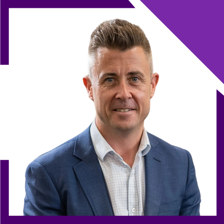 A man in a blue suit and white shirt is smiling for the camera.