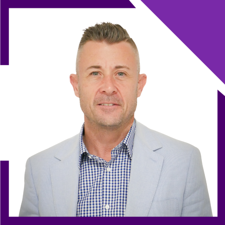 A man in a blue suit and white shirt is smiling for the camera.