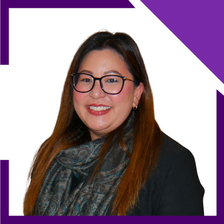 A woman wearing glasses and a black jacket is smiling for the camera.