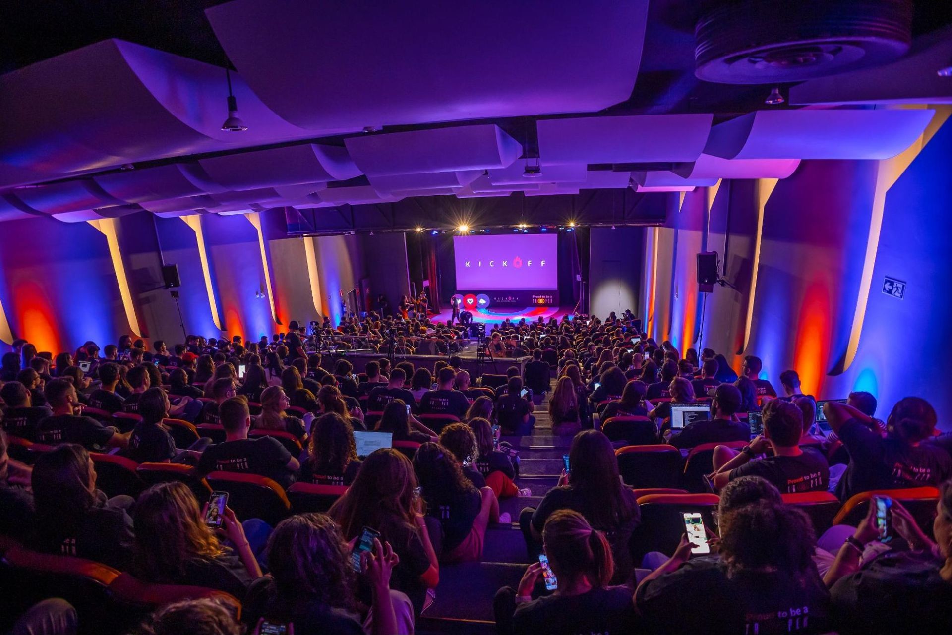 Supernova studio iluminado de azul e vermelho, com a plateia cheia no dia do evento kickoff, onde aconteceram as eleições de 2024 dos HotHeroes.