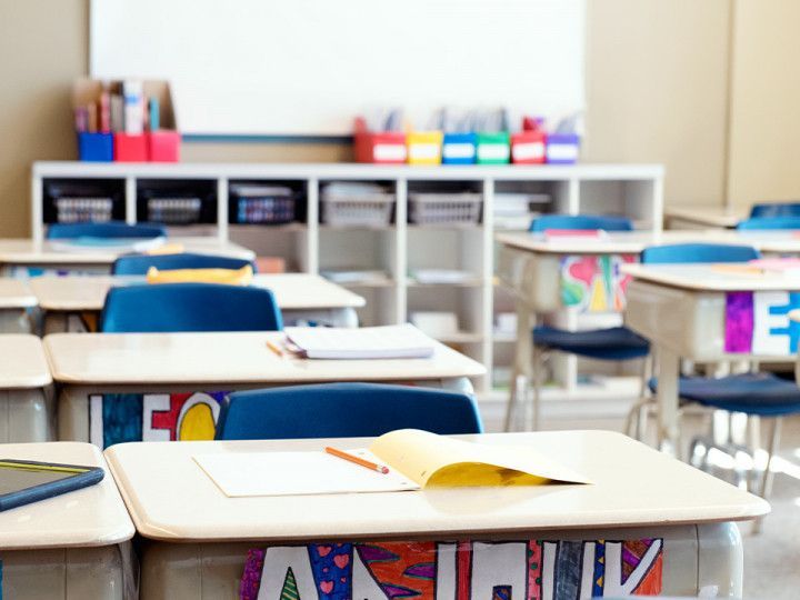 An empty classroom with rows of desks and chairs and a whiteboard.