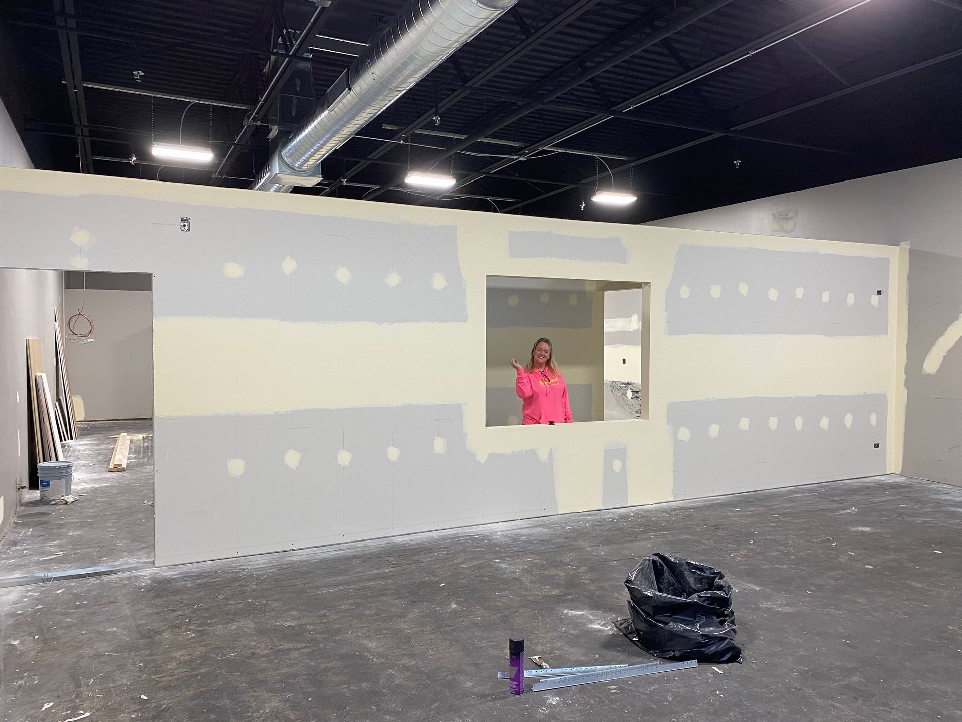 A woman in a pink shirt is standing in an empty room.