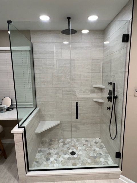A bathroom with a walk in shower with a glass door