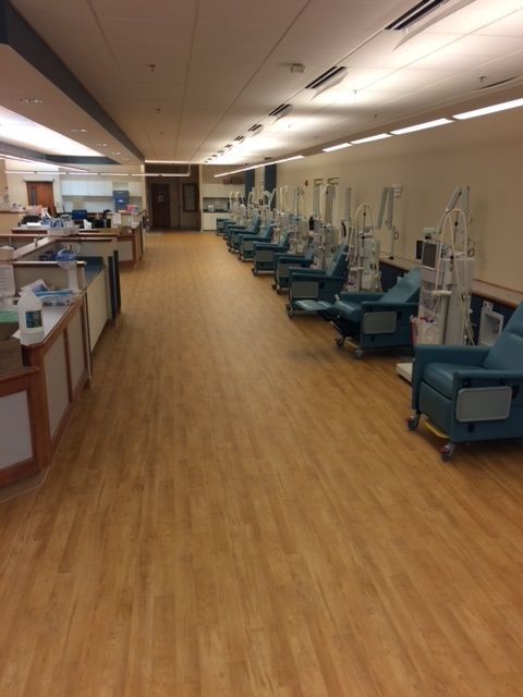 A row of blue chairs are lined up in a hospital room