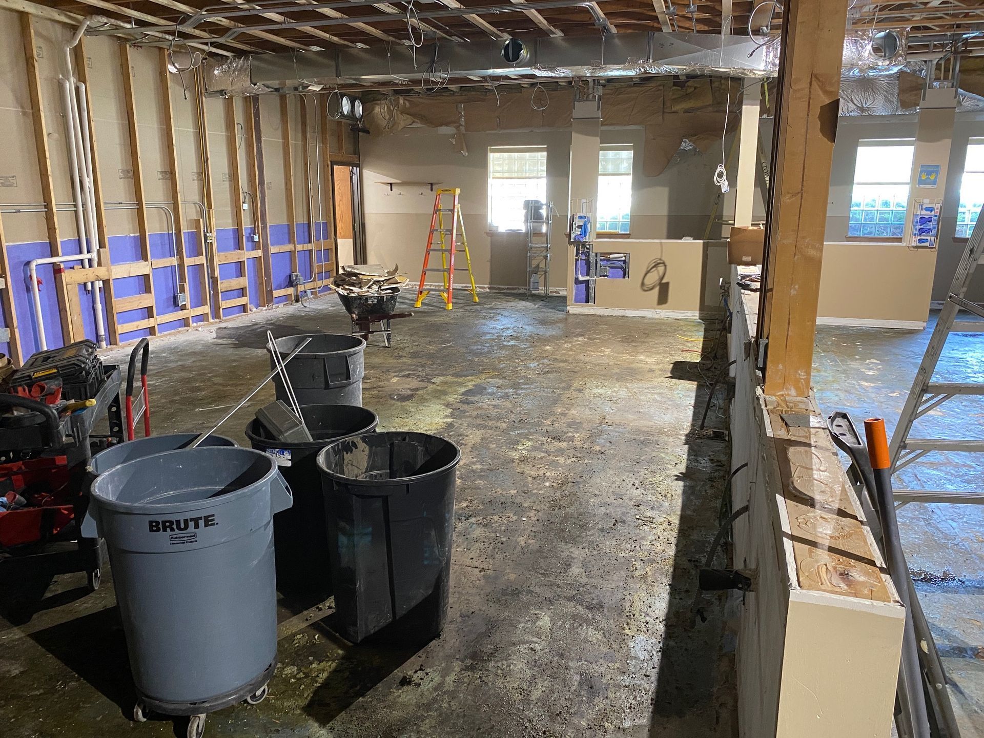 A room with a lot of trash cans and a ladder in it.