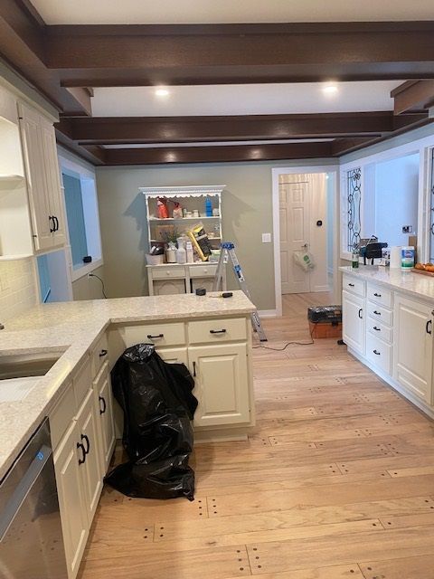 A kitchen with white cabinets and a black bag on the floor