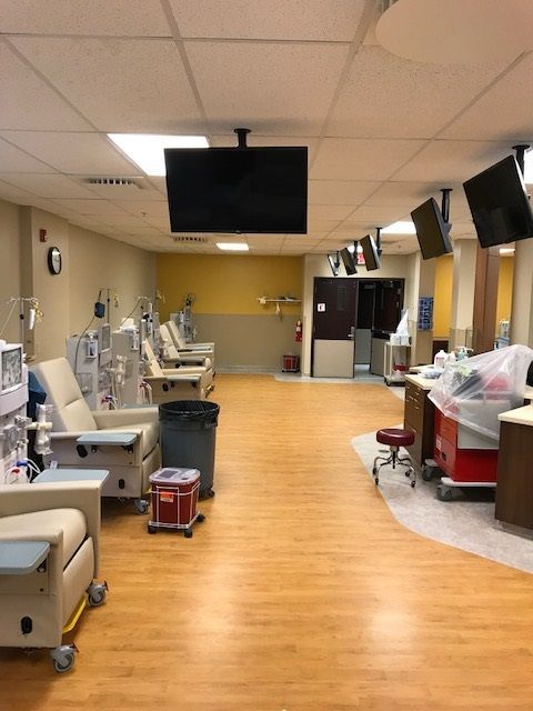 A hospital room with a lot of chairs and a tv on the ceiling