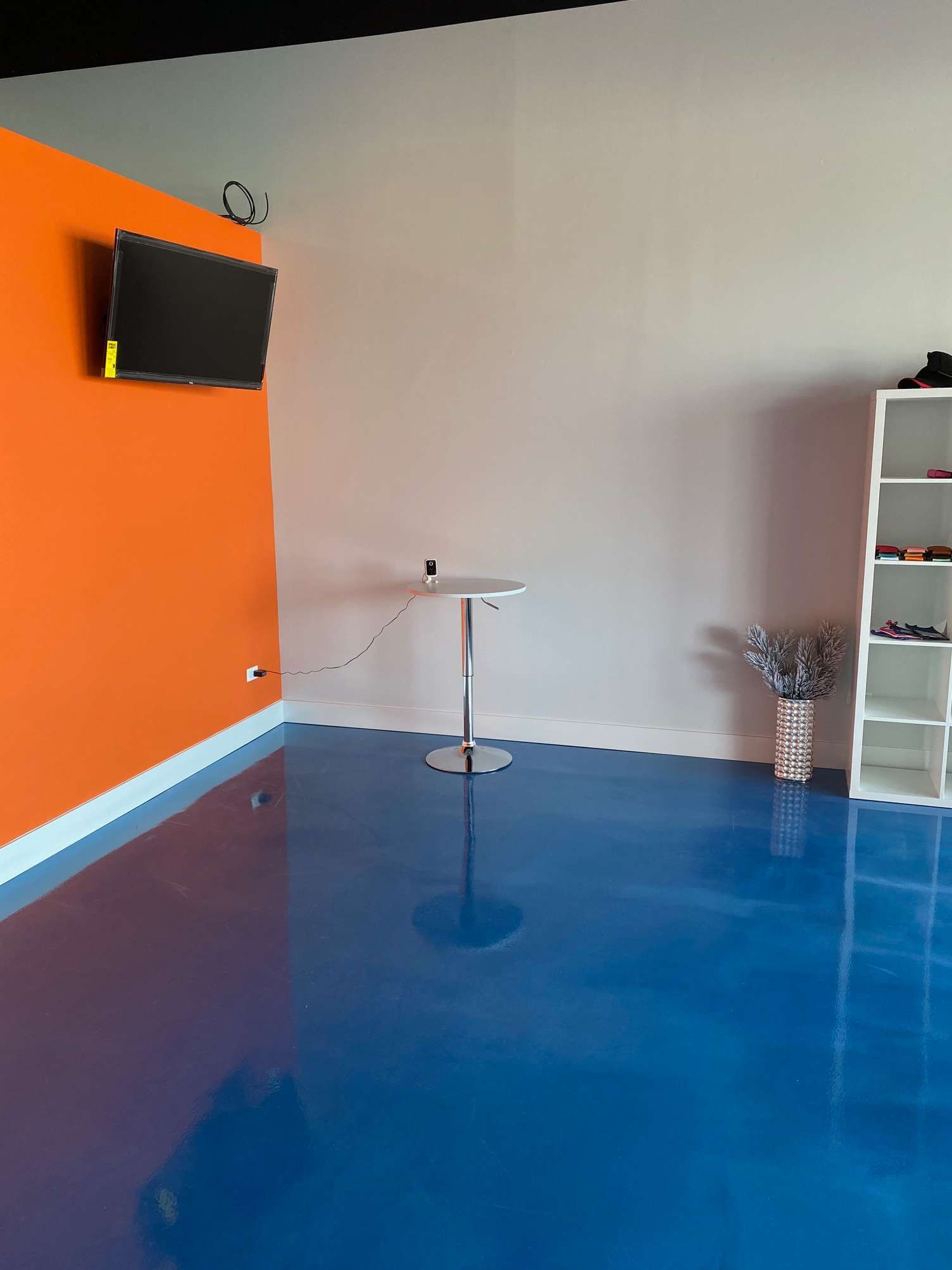 A room with a blue floor and a tv on the wall