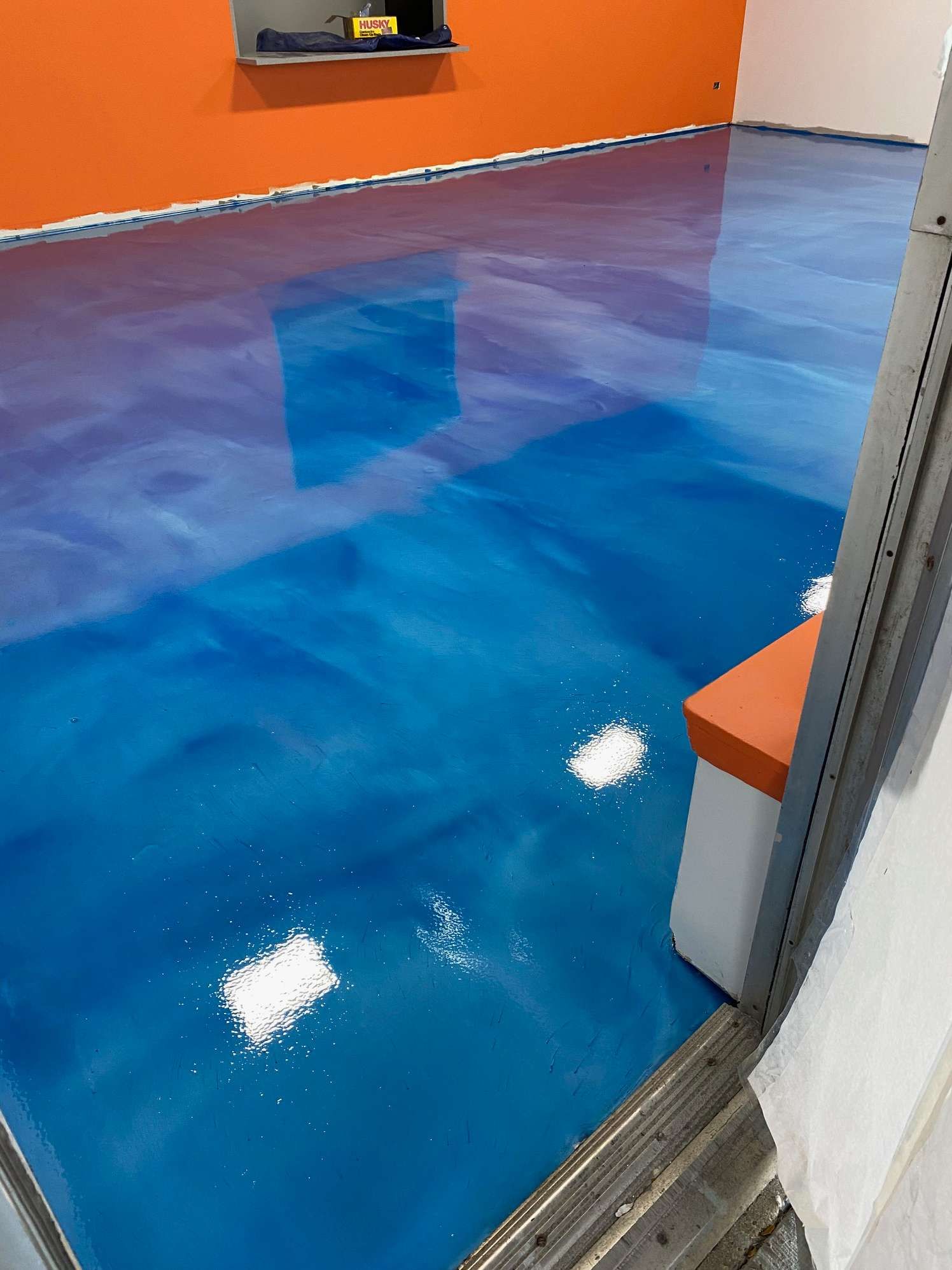 A blue and purple metallic floor in a room with orange walls.