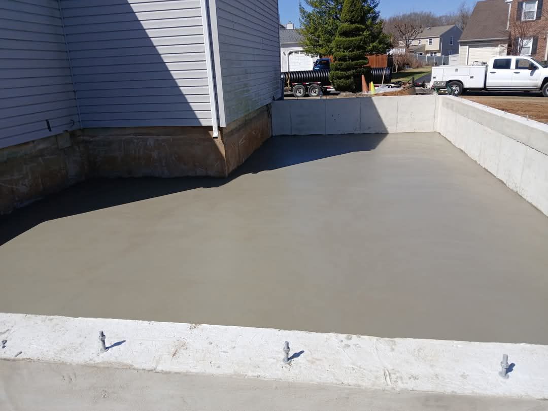 Concrete patio beside a house with white retaining walls on a sunny day