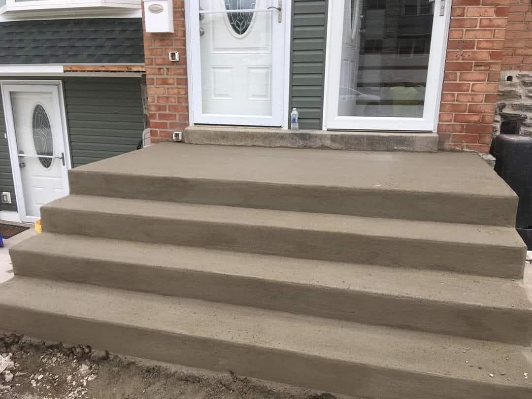 Front porch with wide concrete steps leading to a white front door on a brick house
