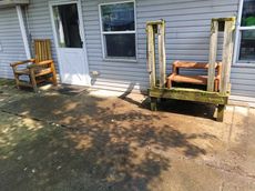 Wooden chair and steps by a back door on a concrete patio.