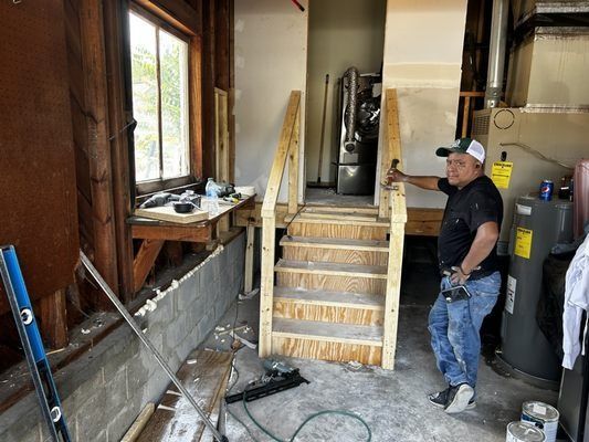 A man is standing in a room with stairs being built.