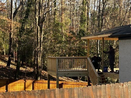 A house with a deck and a fence in the woods.