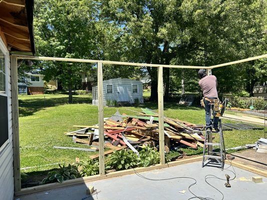 A man is standing on a ladder working on a deck.