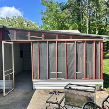 A screened in porch with a table and chairs in front of it.