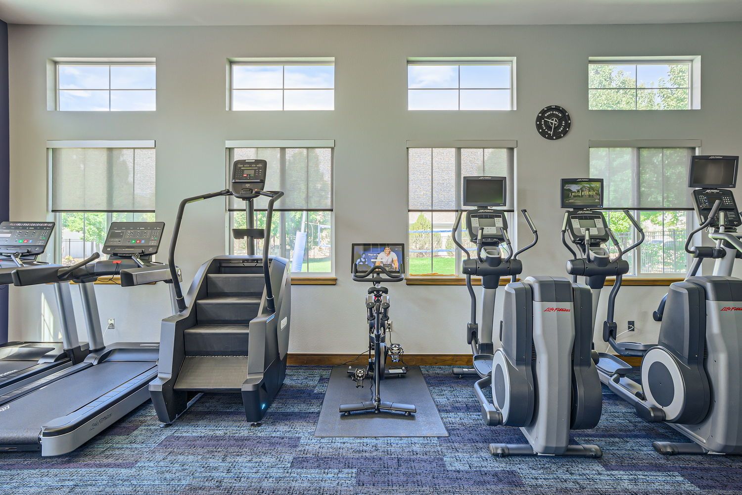 Fitness center with treadmills, ellipticals, and a stationary bike by large windows.