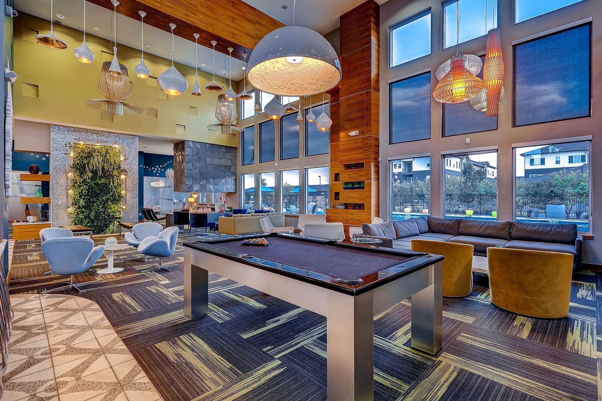 Modern communal lounge with a pool table, contemporary seating, and large windows.