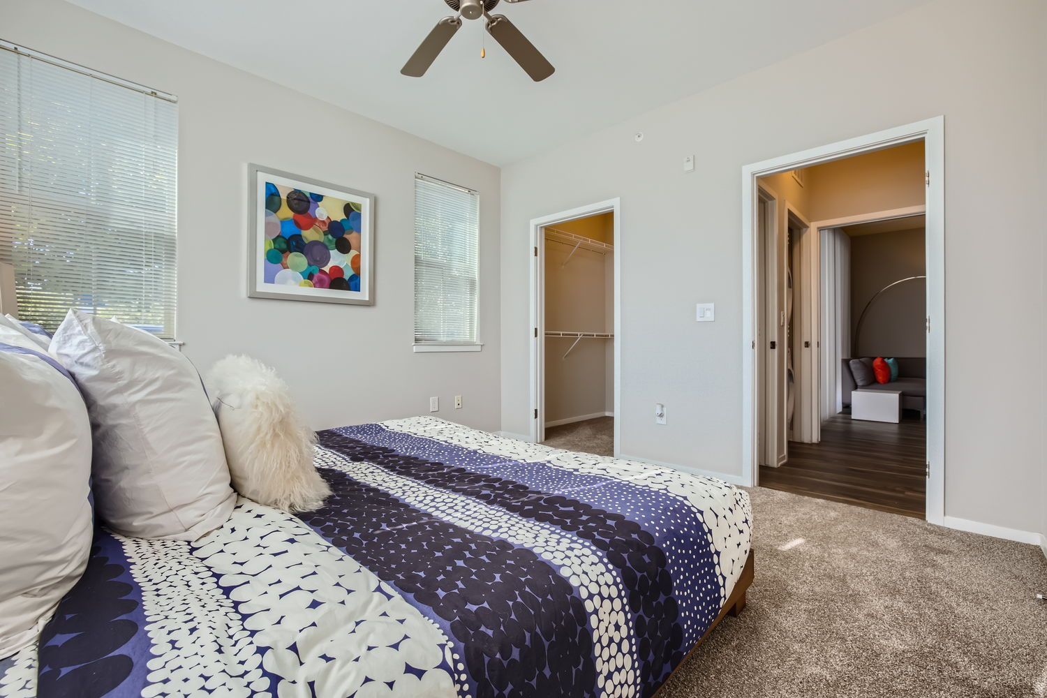 Bedroom with a bed, two windows with blinds, an open closet, and a ceiling fan.