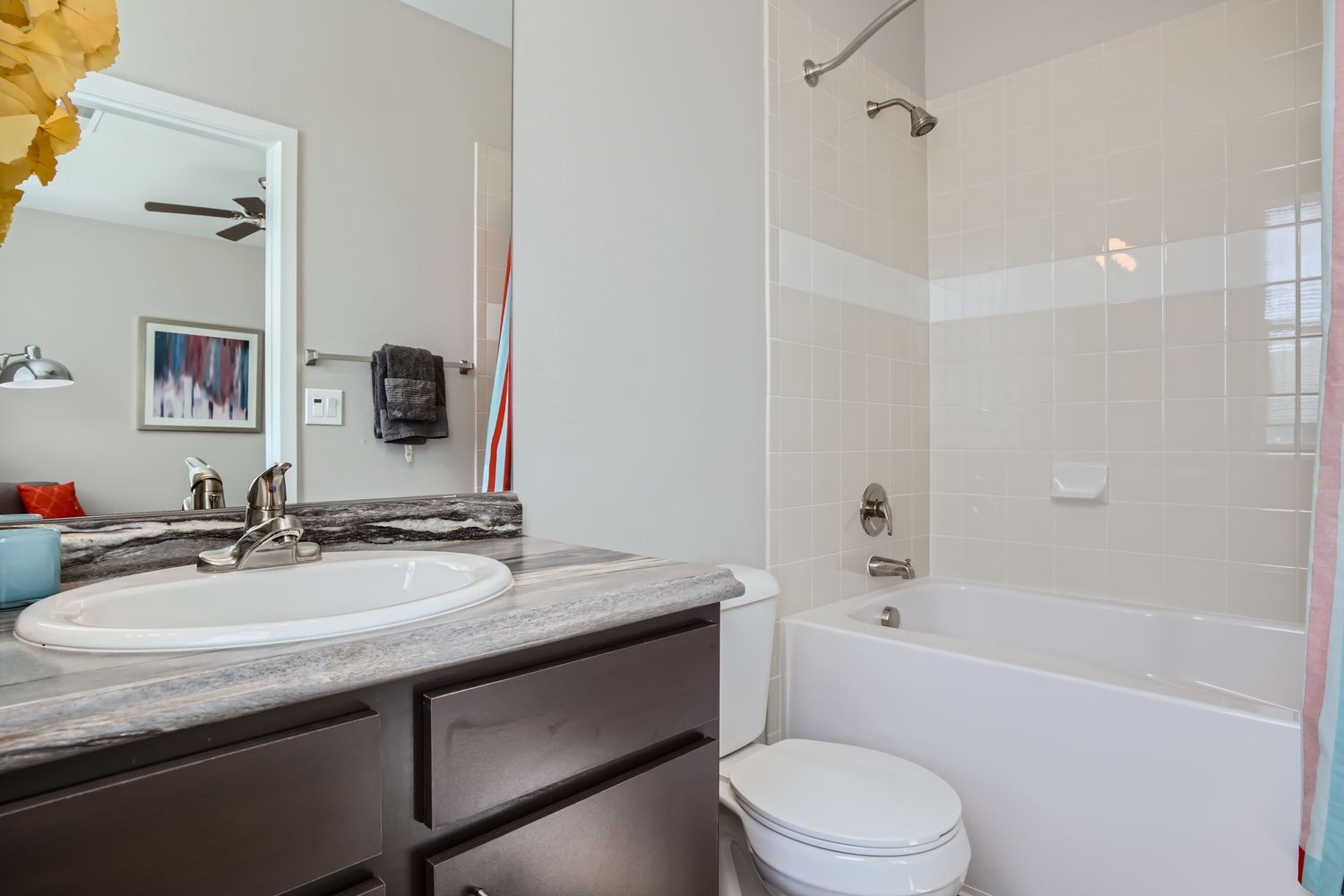 Bathroom with sink, vanity, toilet, and tiled bathtub/shower.