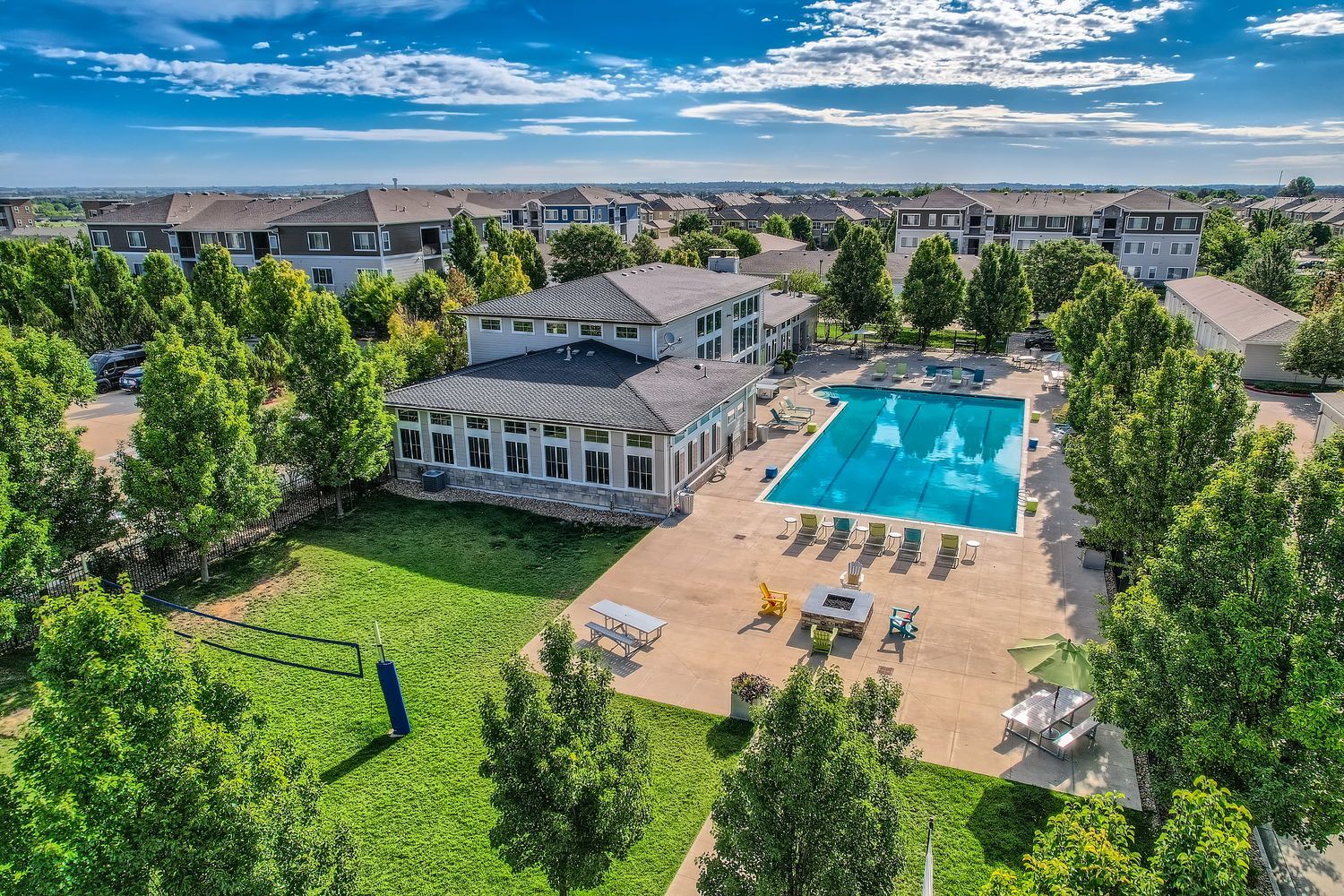 Aerial view of an apartment community pool with lounge chairs and a clubhouse.