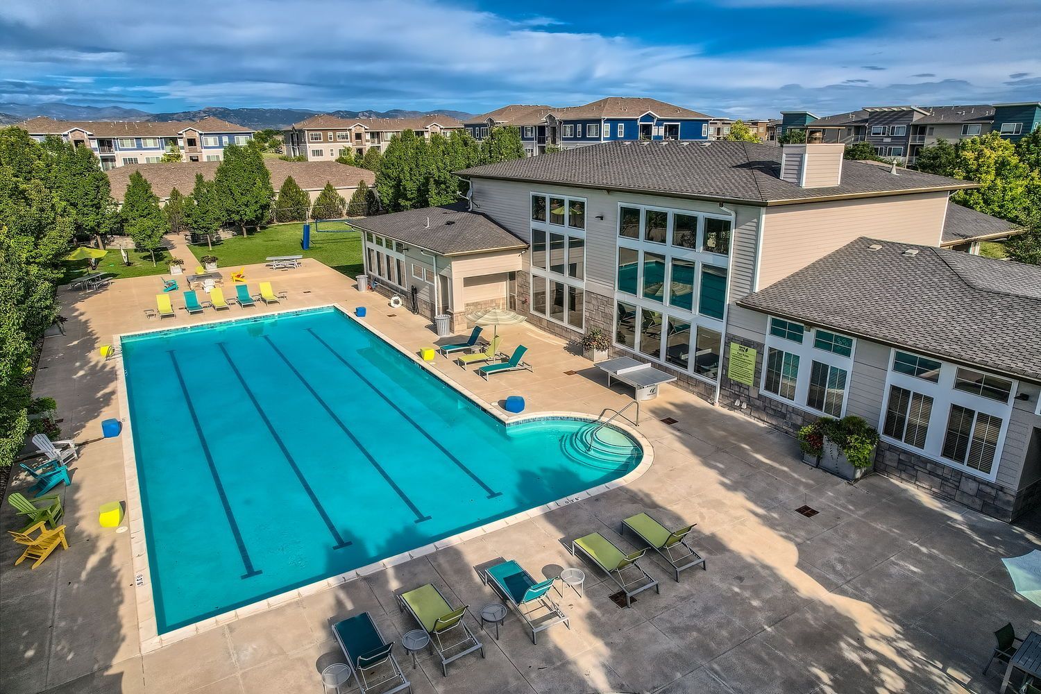 Aerial view of apartment complex pool and clubhouse on a sunny day.