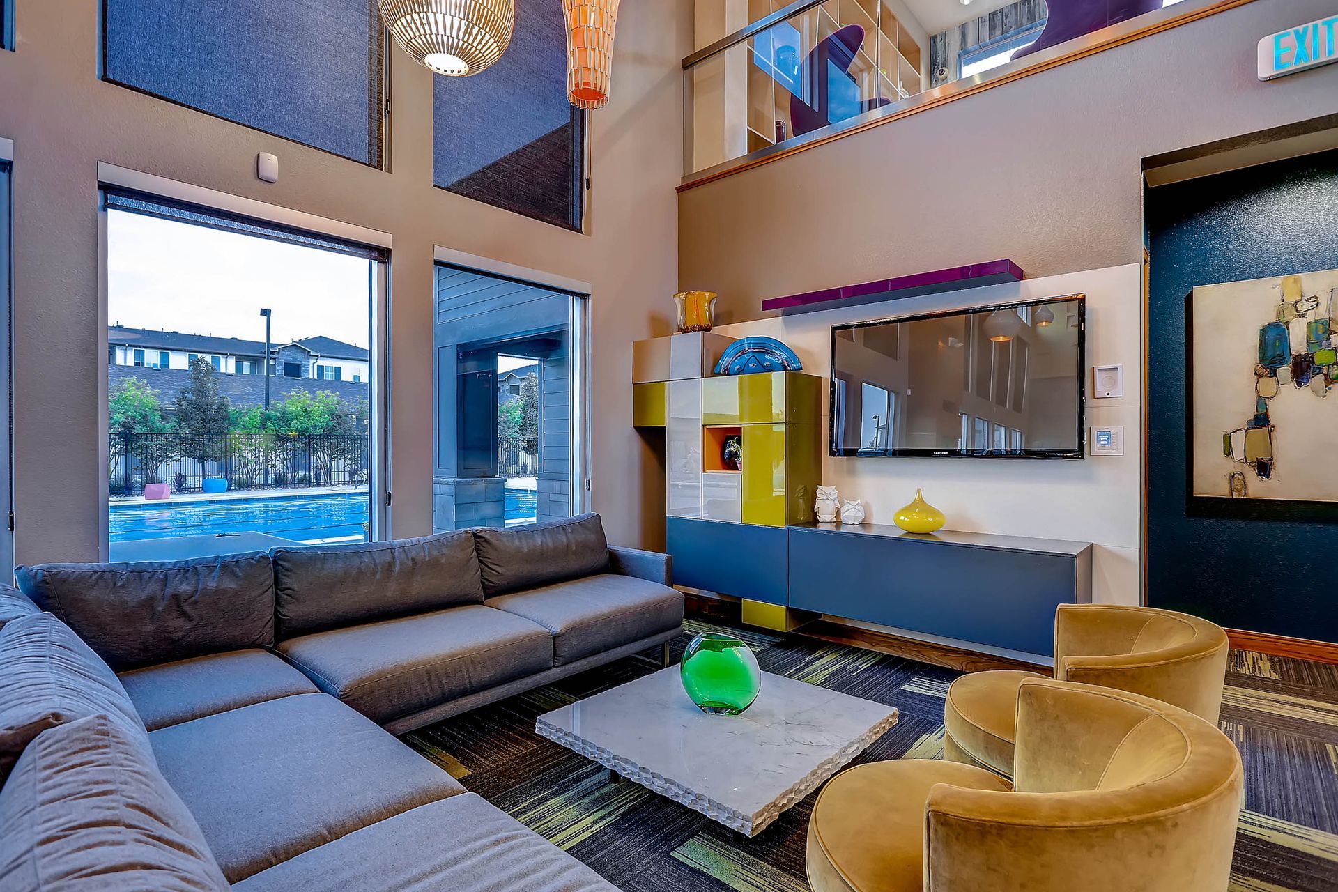 Modern lounge area with a sectional sofa, two armchairs, a large window, and a TV.