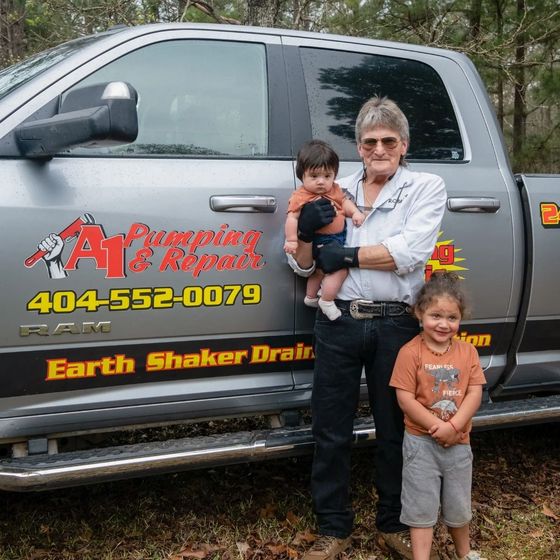 A man and two children are standing in front of a truck that says earth shaker drain