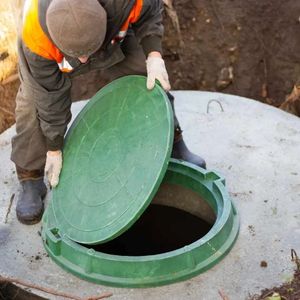 A man is opening a green manhole cover