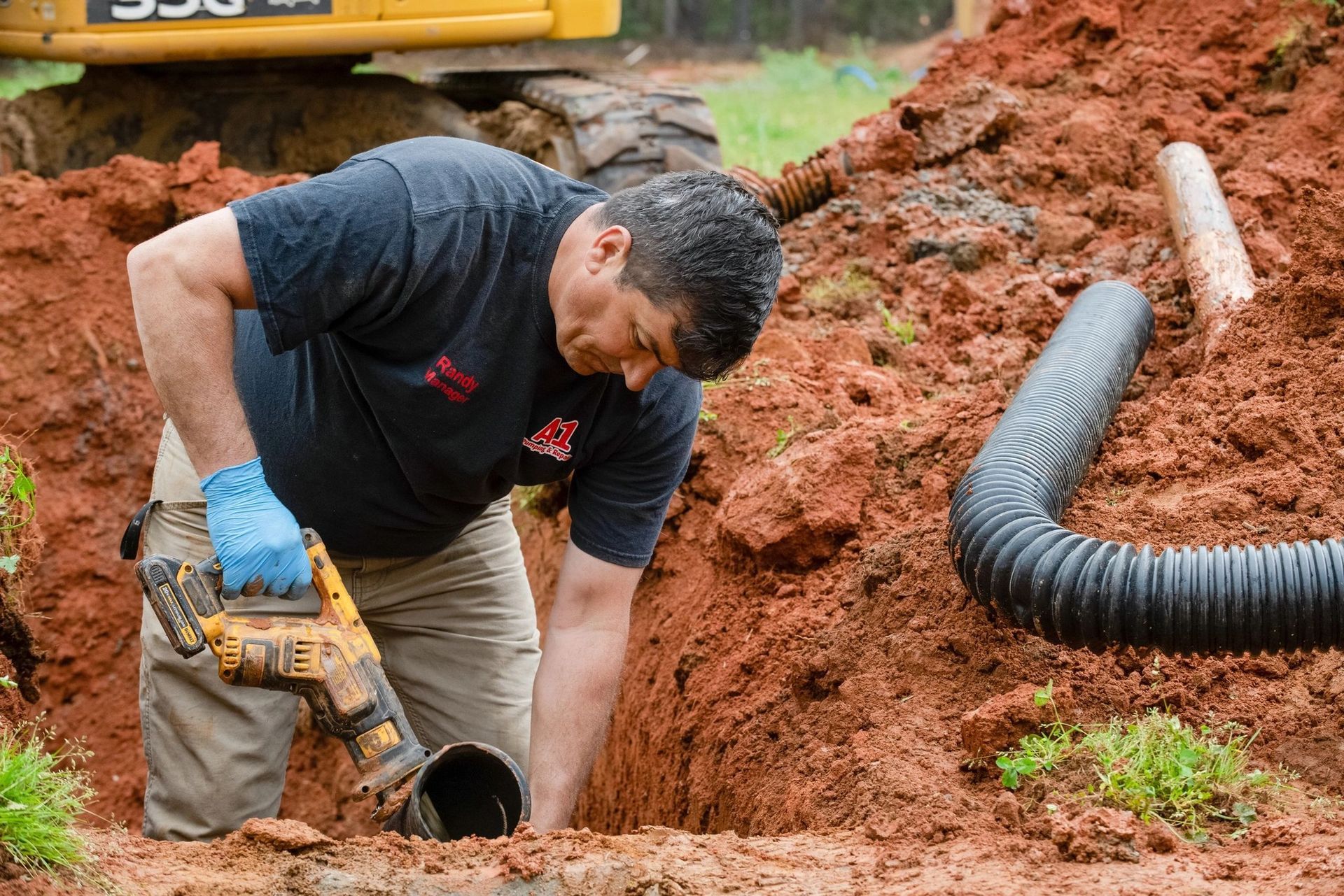 A man is digging a hole in the dirt with a drill.