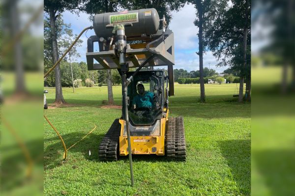 A yellow bulldozer is sitting on top of a lush green field.