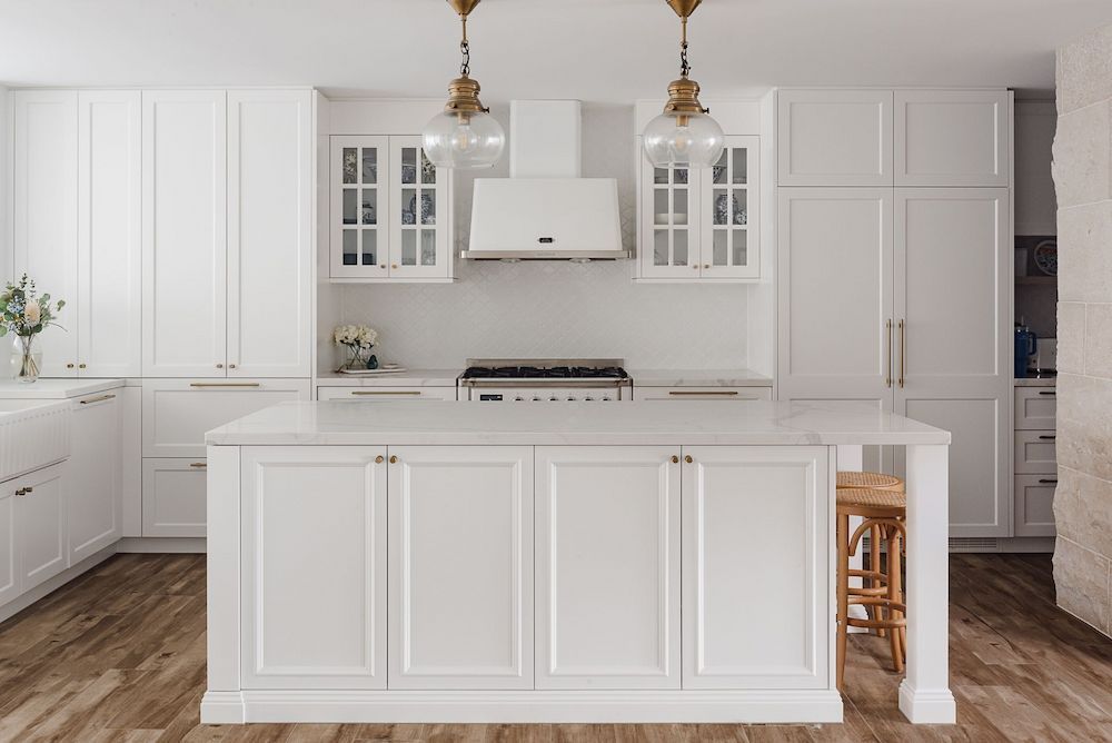 A Kitchen With White Cabinets, a Stove, and a Large Table— Mylec Electrical Solutions in North Wollongong, NSW