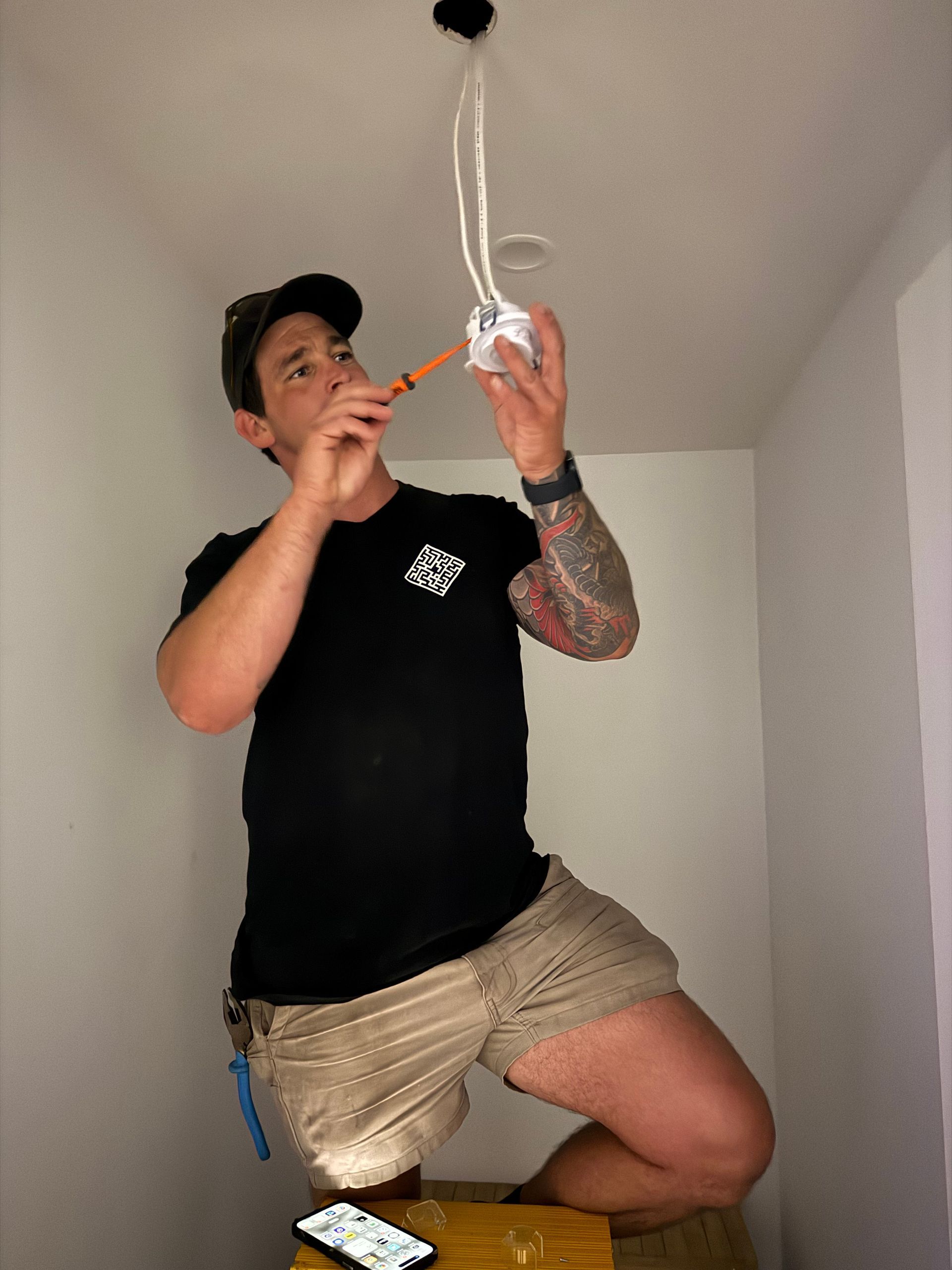 A man is measuring a light fixture with a tape measure — Mylec Electrical Solutions in Shell Cove, NSW