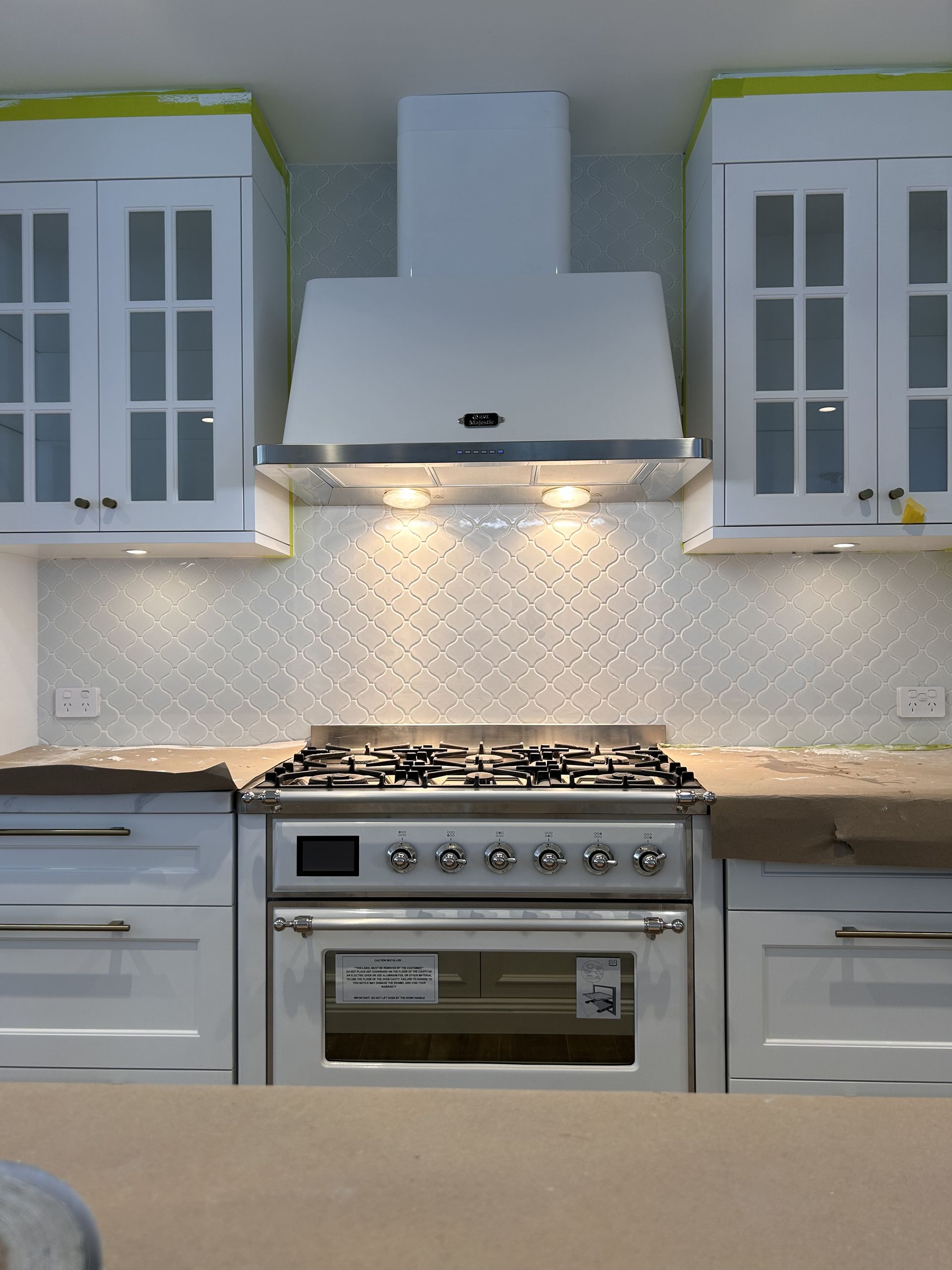 A kitchen with white cabinets and a stove top oven — Mylec Electrical Solutions in Shell Cove, NSW