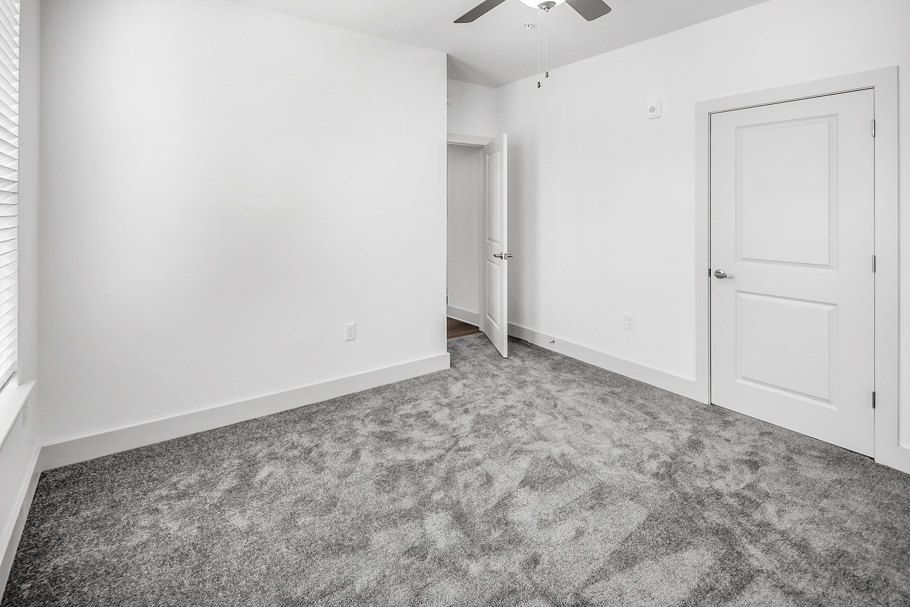 Empty bedroom with gray carpet, white walls, a door, and closet.