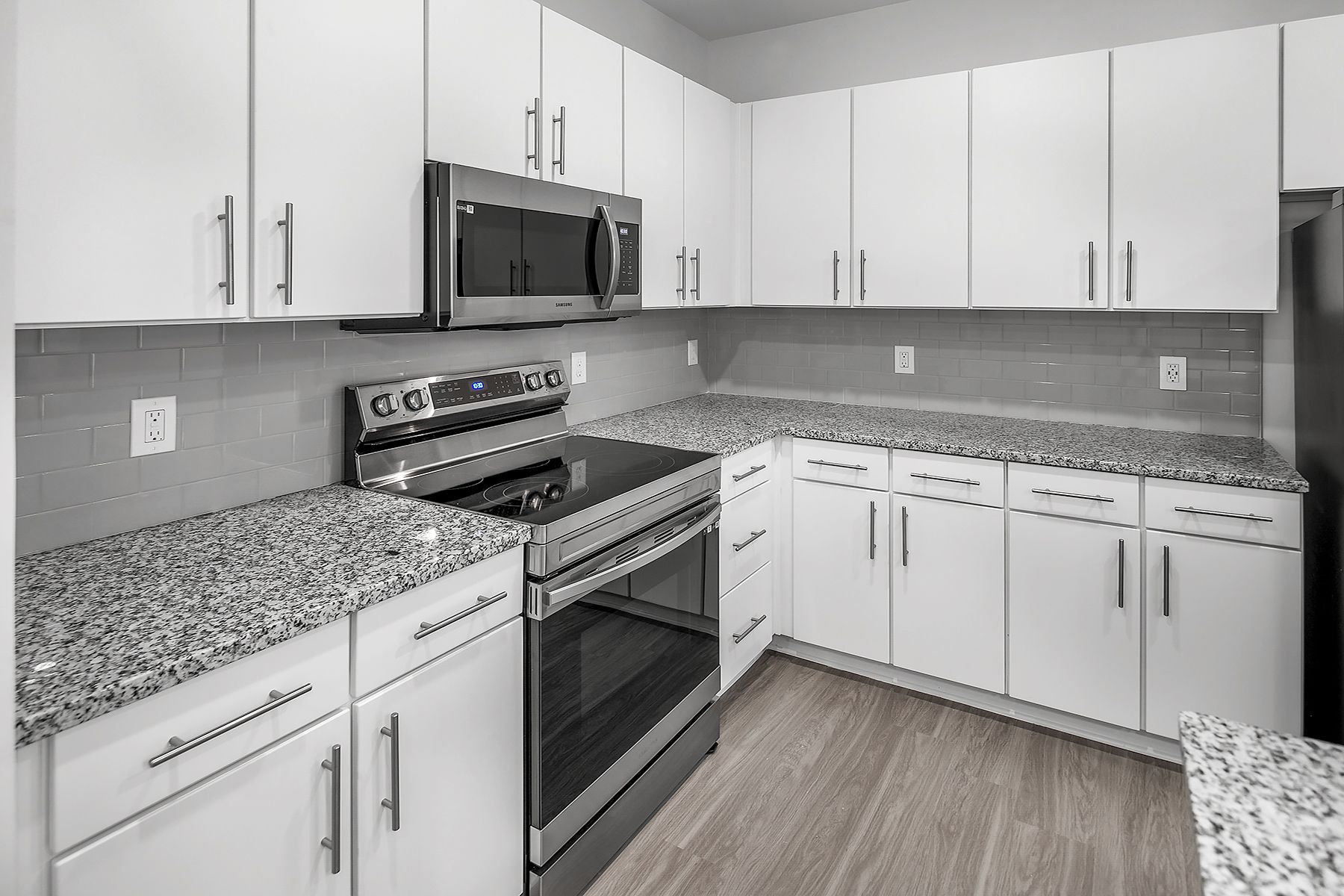 Bright white kitchen with granite countertops and stainless steel appliances.