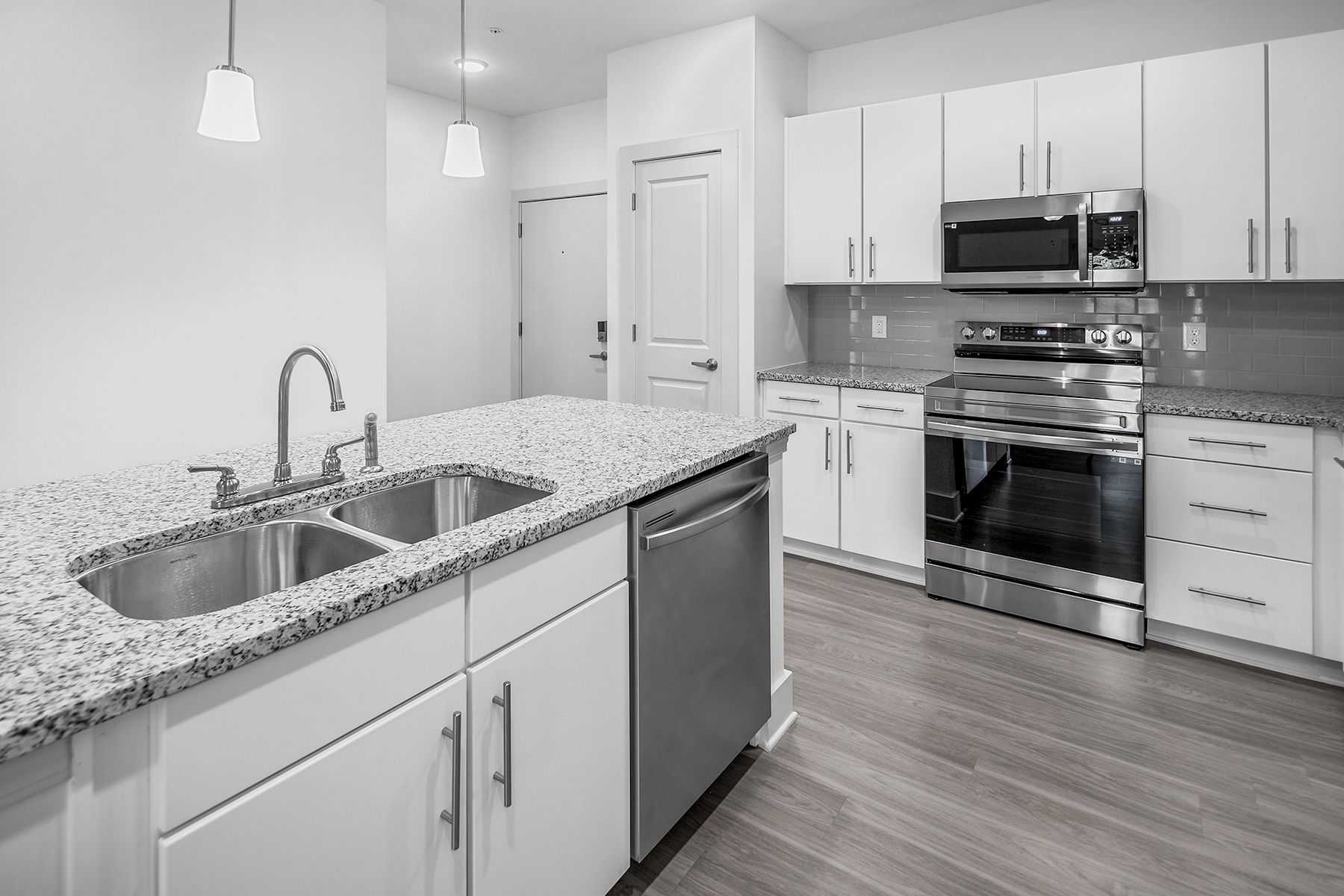 Modern kitchen with white cabinets, granite countertops, and stainless steel appliances.