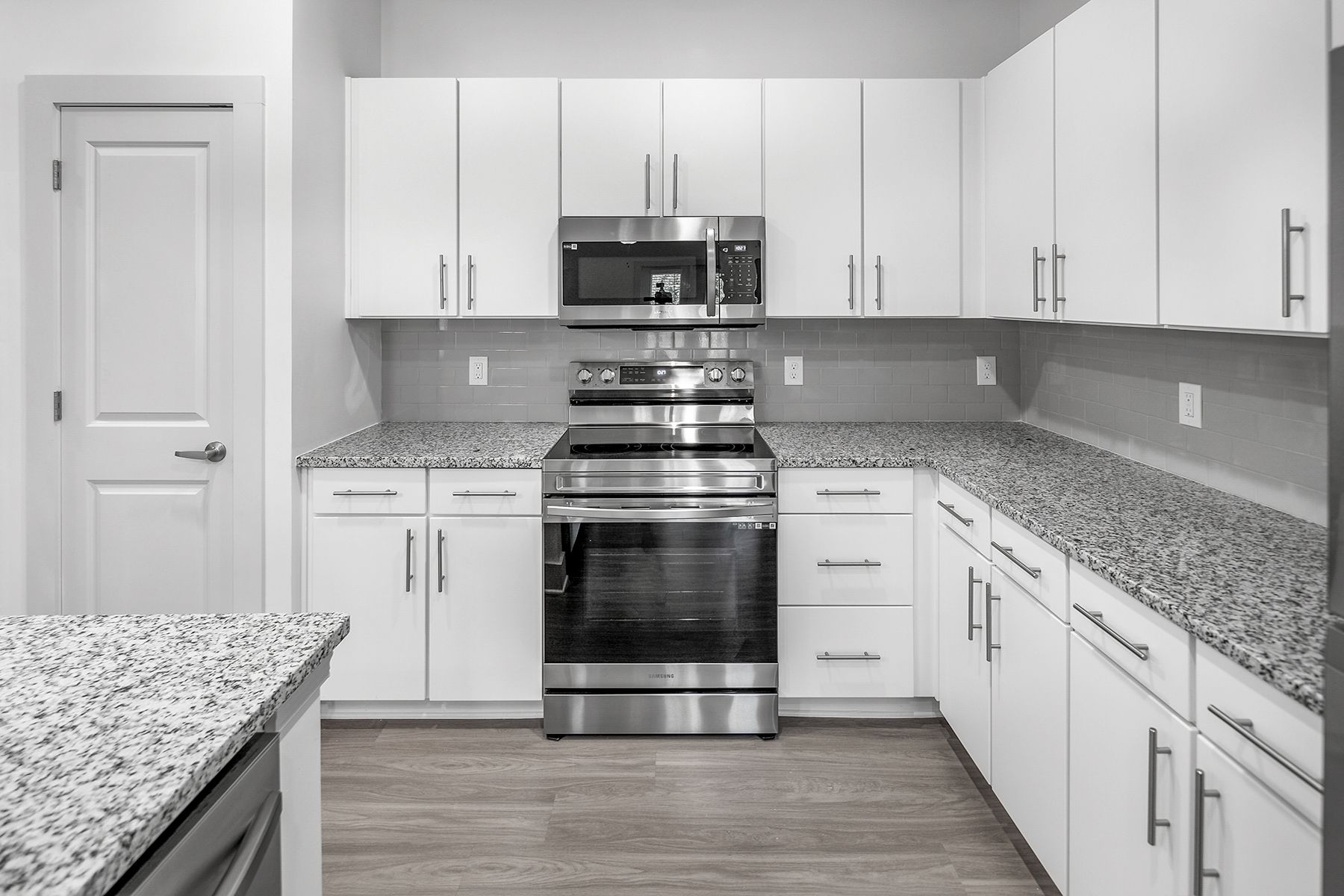 Modern kitchen with white cabinets, granite countertops, and stainless steel appliances.