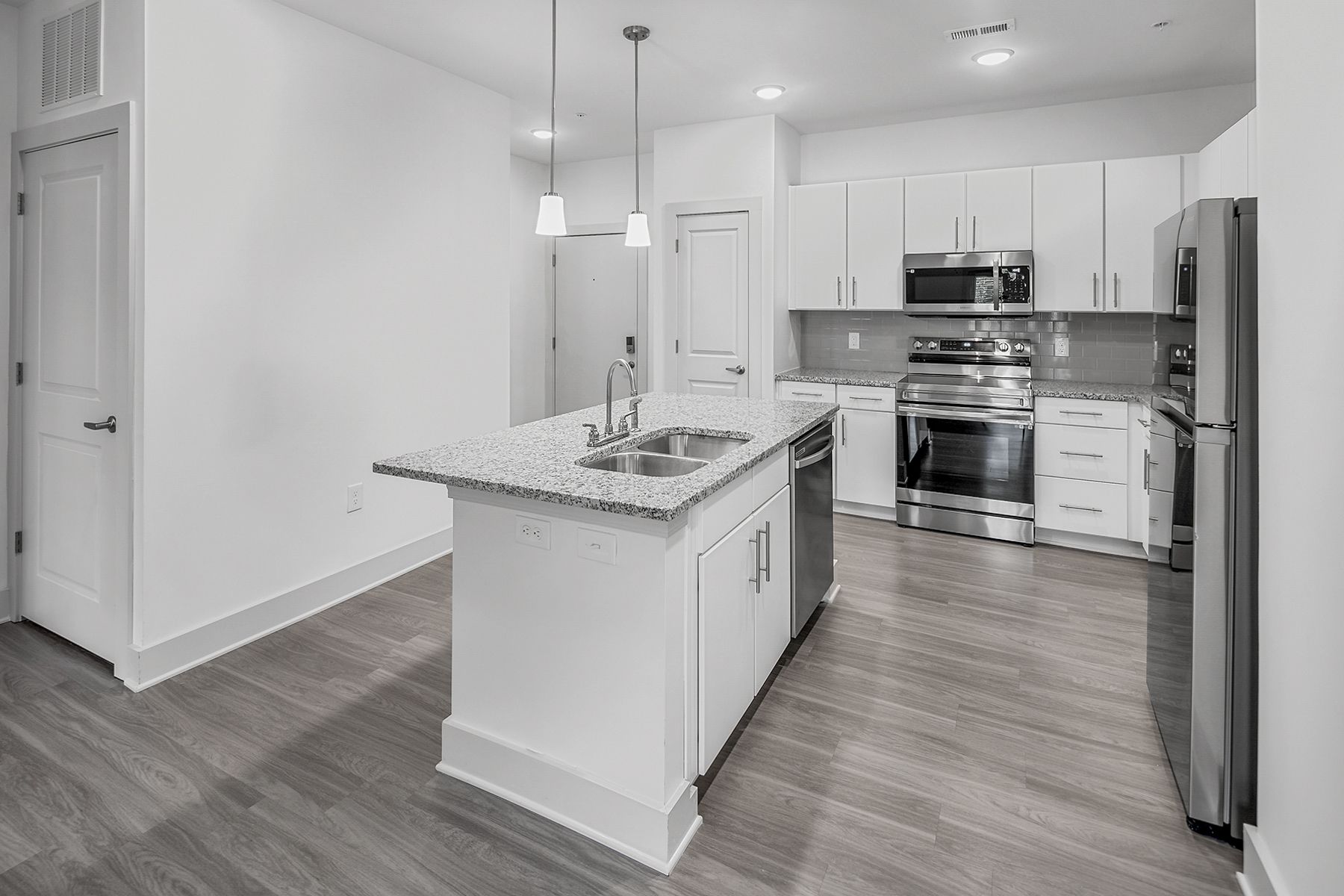 Modern kitchen with white cabinets, stainless steel appliances, and a gray granite island.