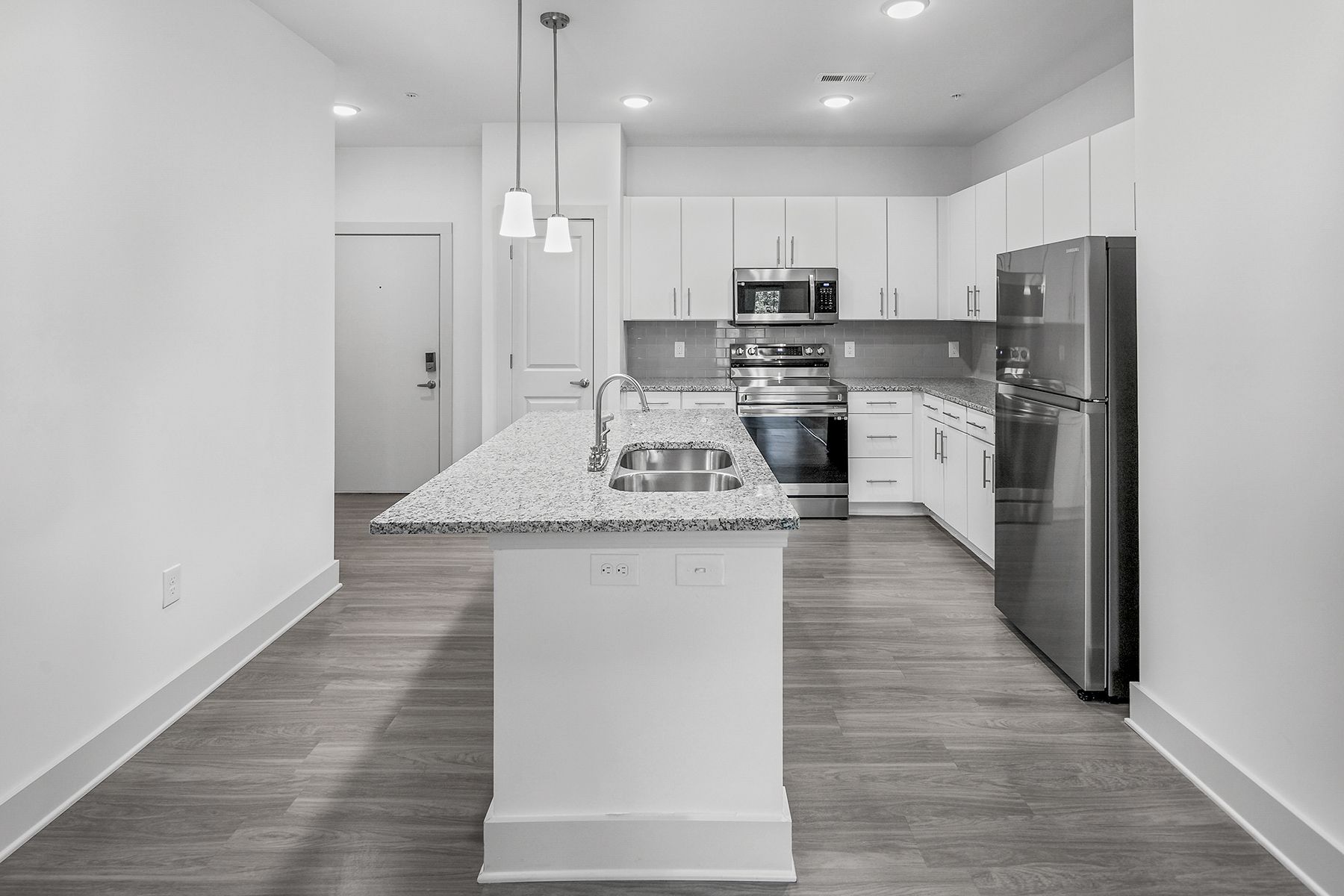 Modern kitchen with white cabinets, granite countertops, stainless steel appliances.