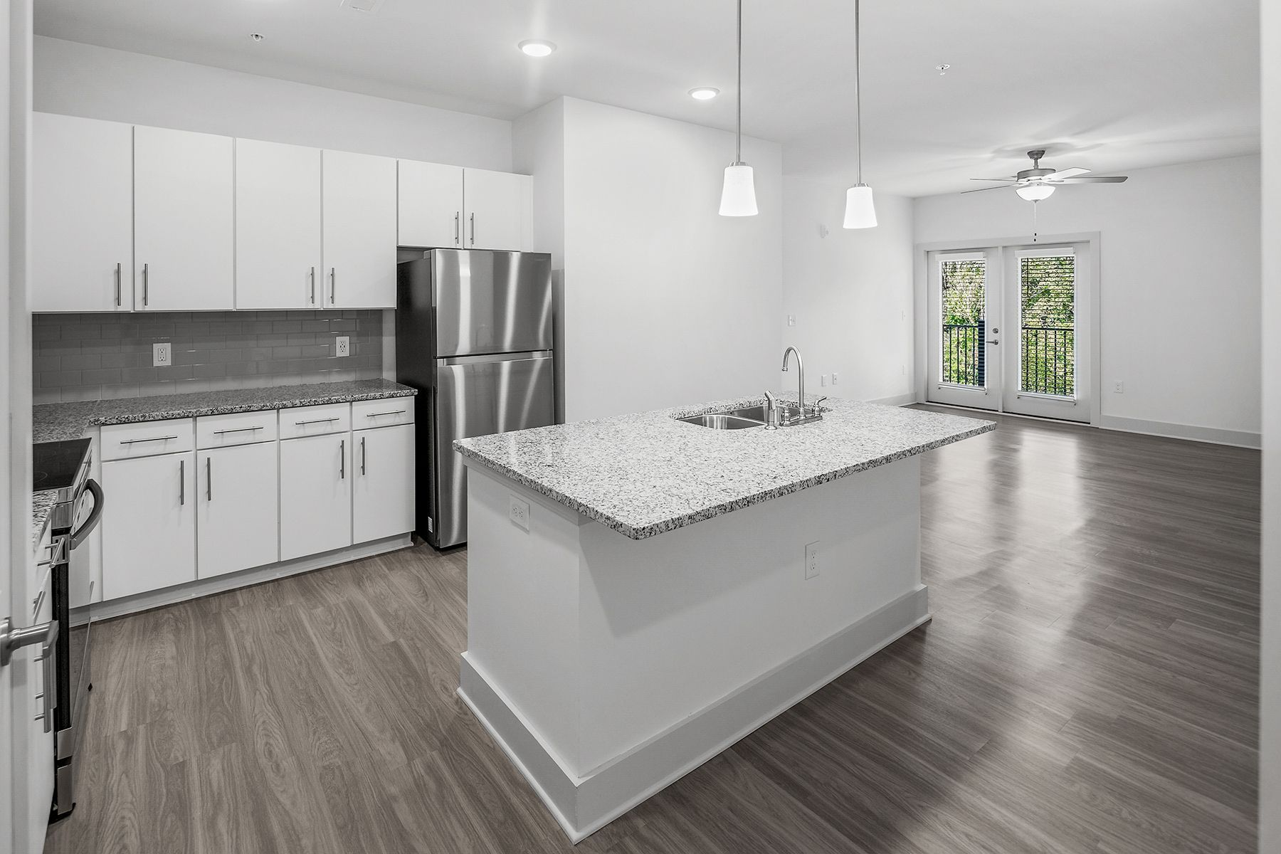 Modern kitchen with white cabinets, stainless steel appliances, and island with granite countertop.