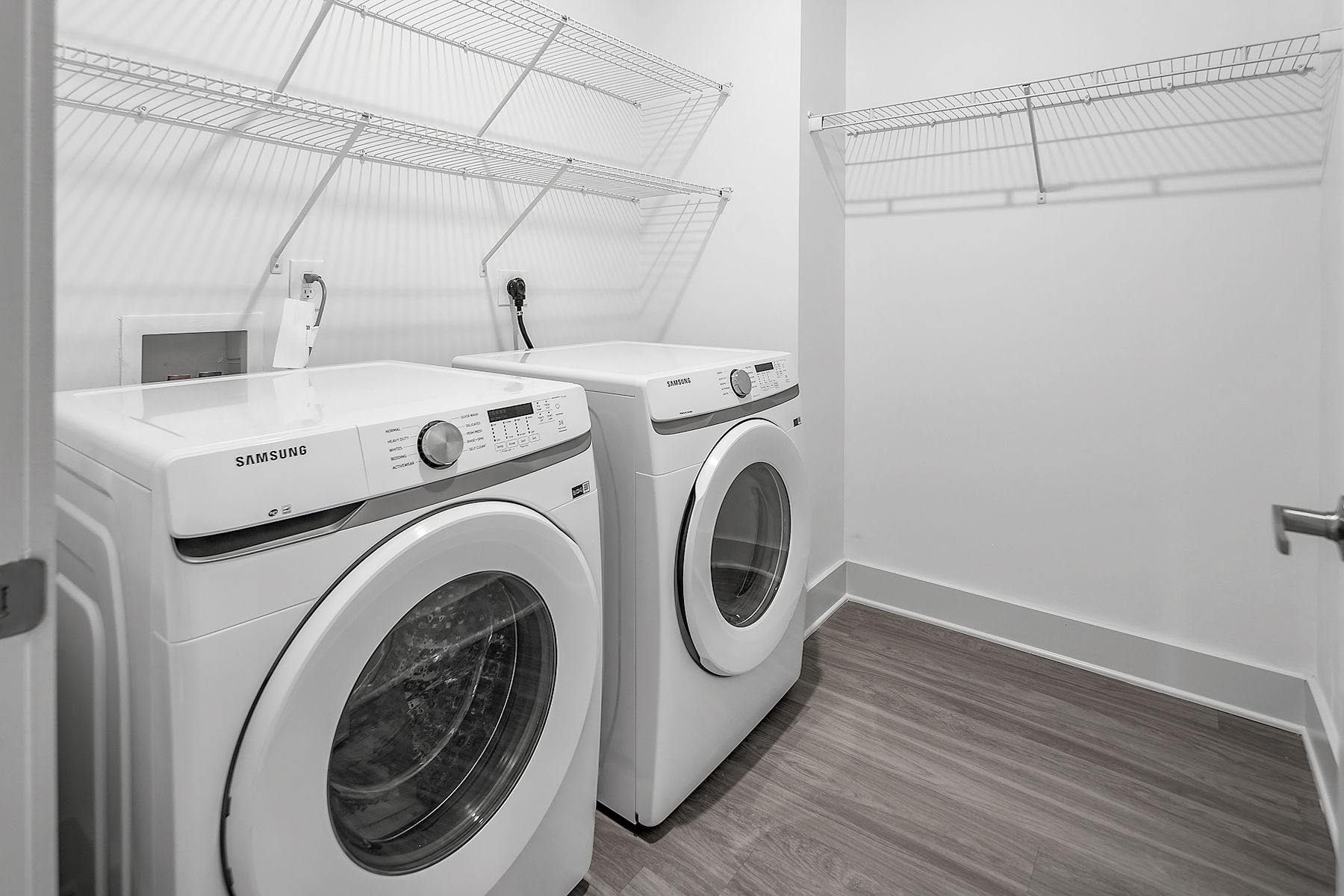 Laundry room with white washer and dryer, wire shelving, and gray flooring.