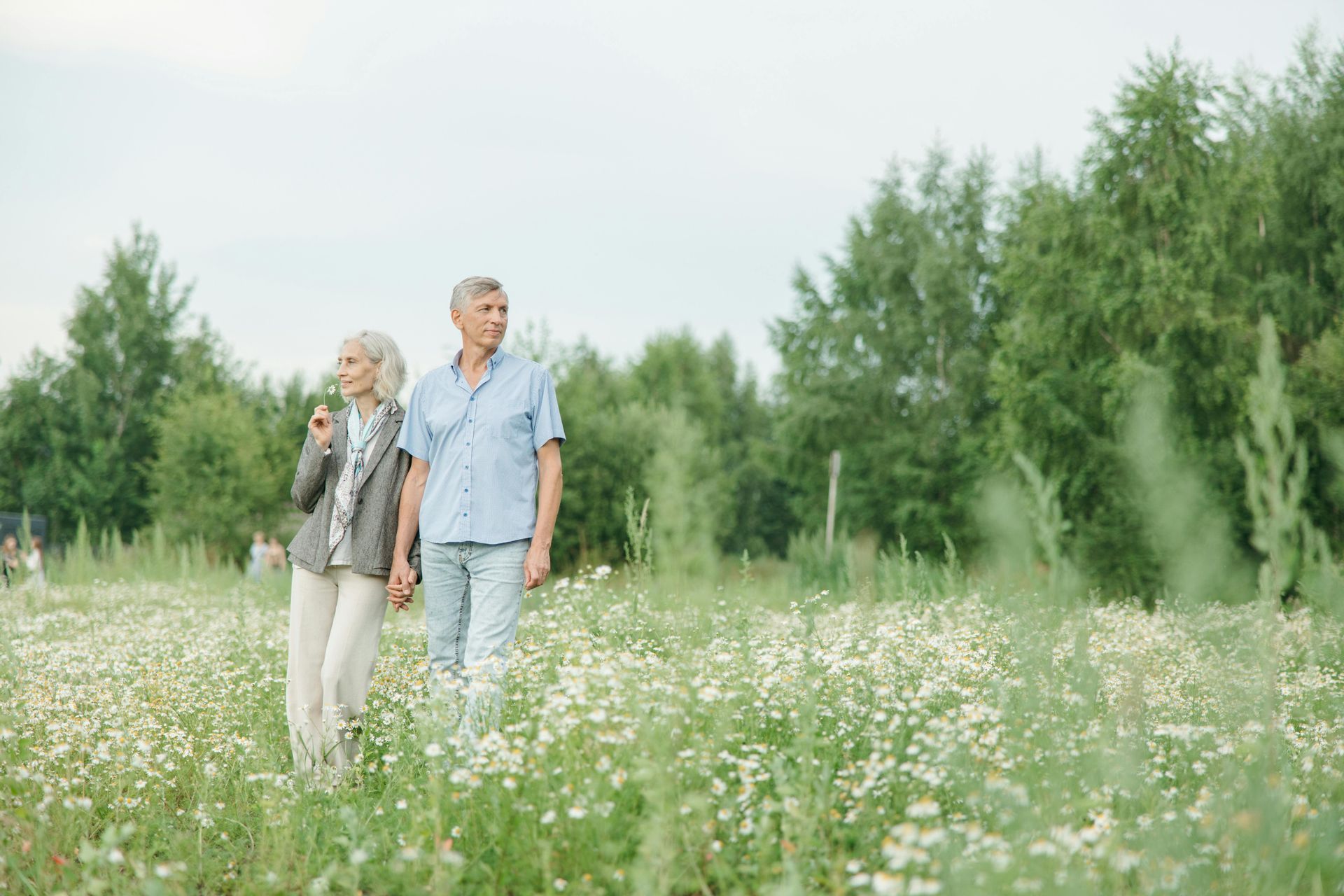 A man and a woman are walking through a field of flowers.