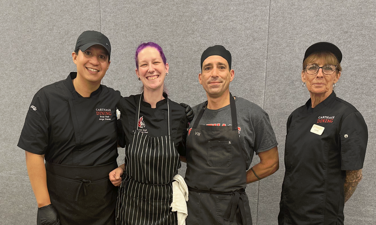 A group of chefs are posing for a picture in a kitchen.