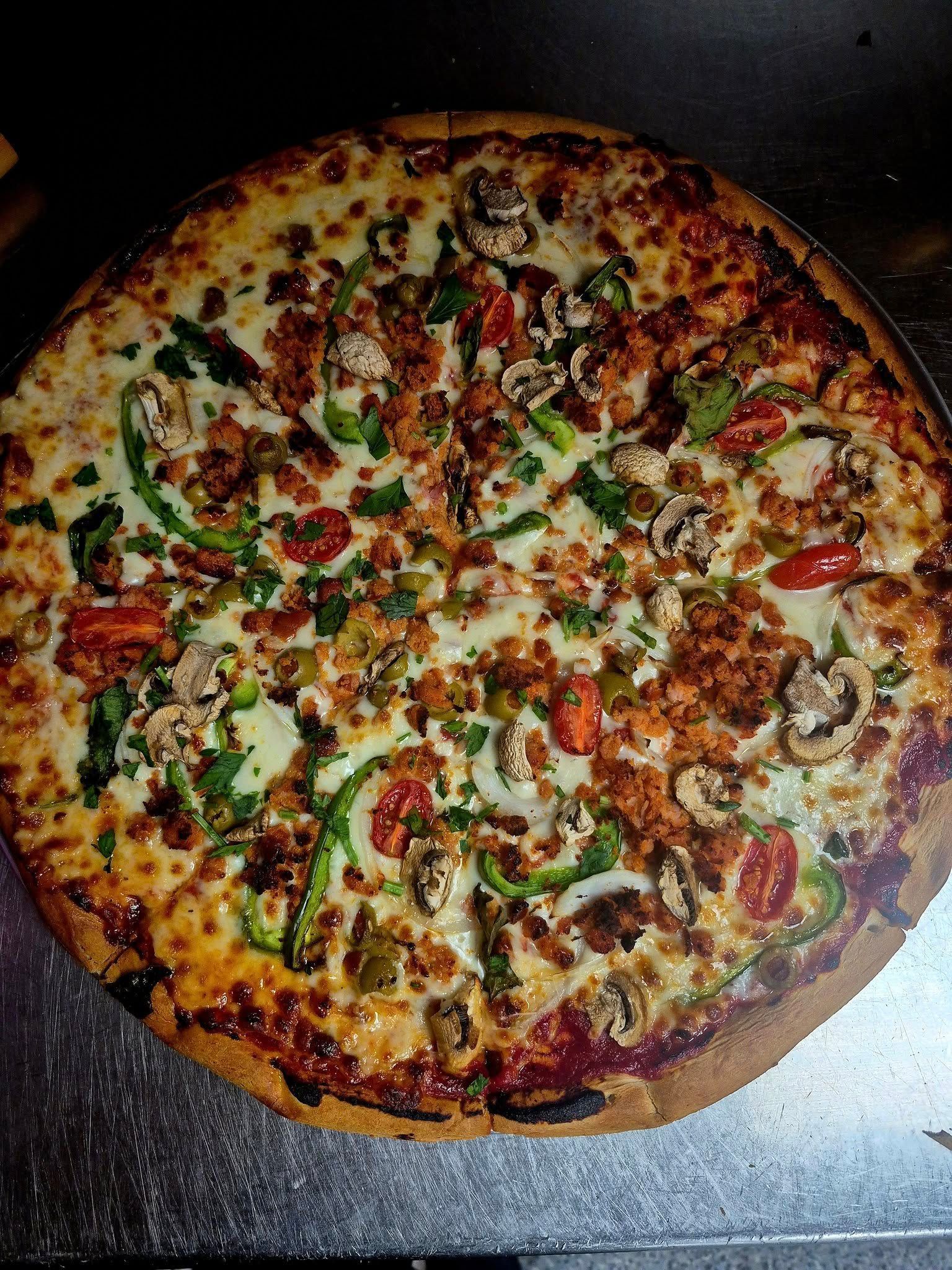 Large pizza with toppings: green peppers, mushrooms, tomatoes, meat, and cheese.