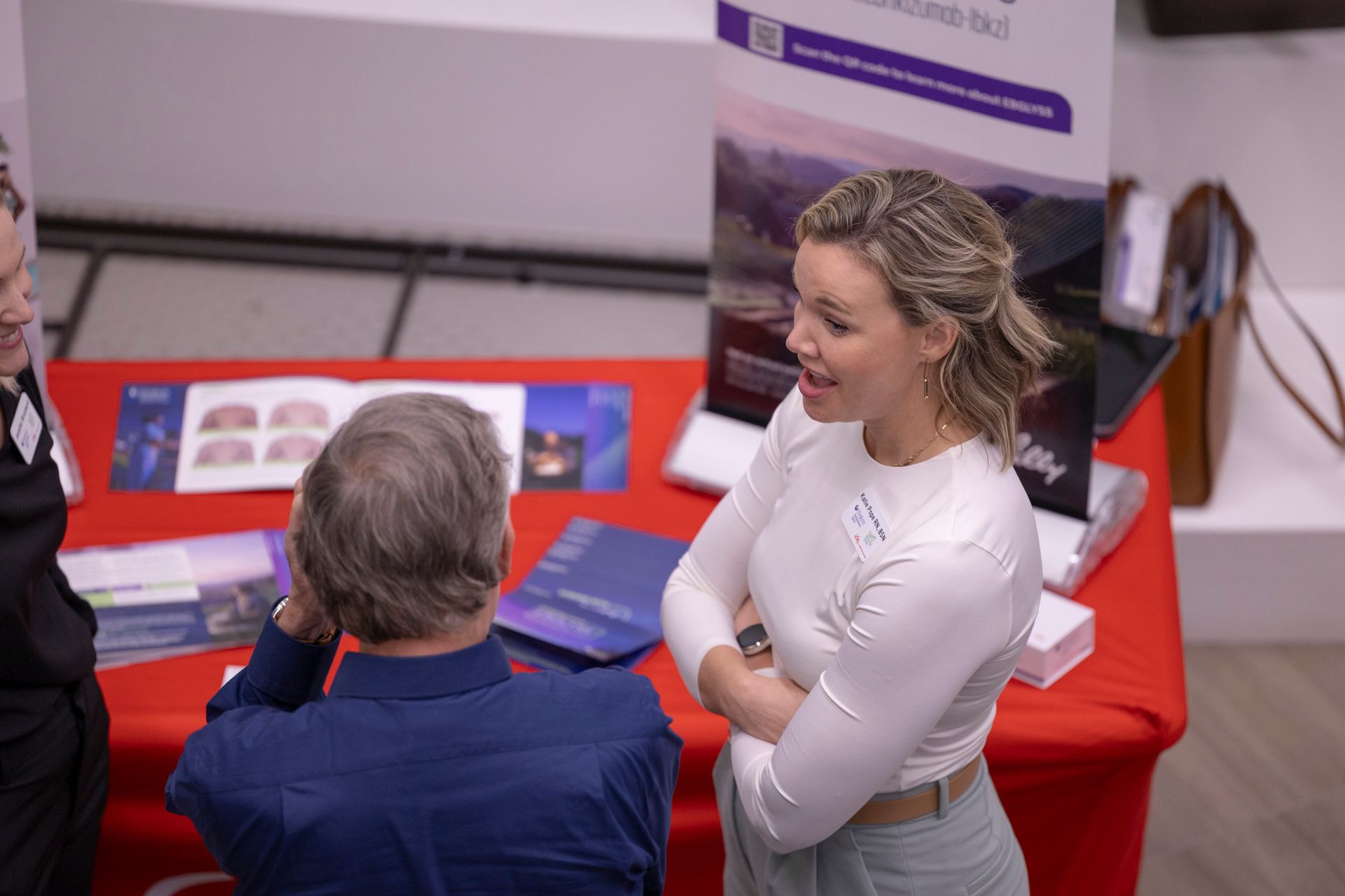 A group of people are standing around a table talking to each other.