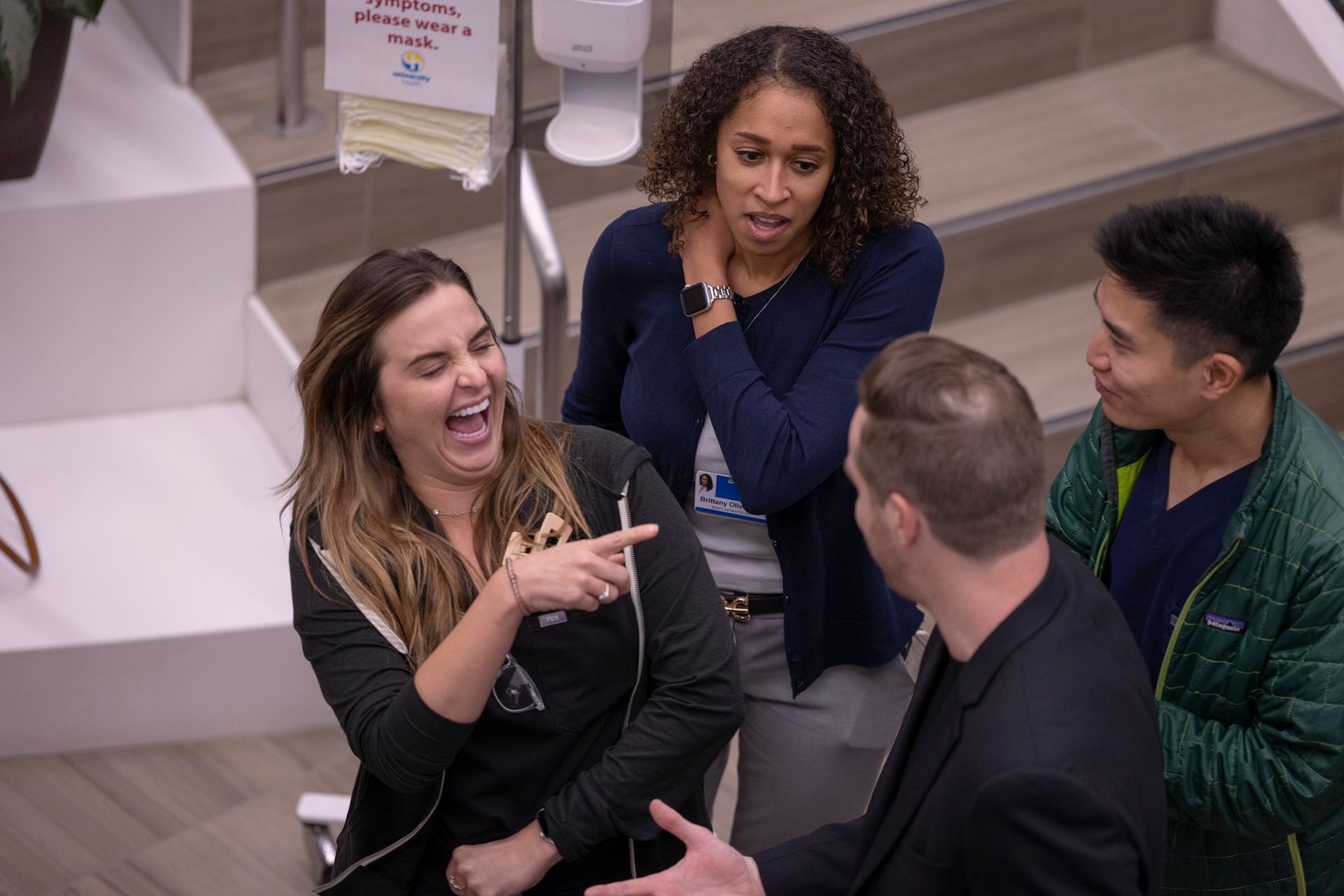 A group of people are laughing together in a hospital lobby.