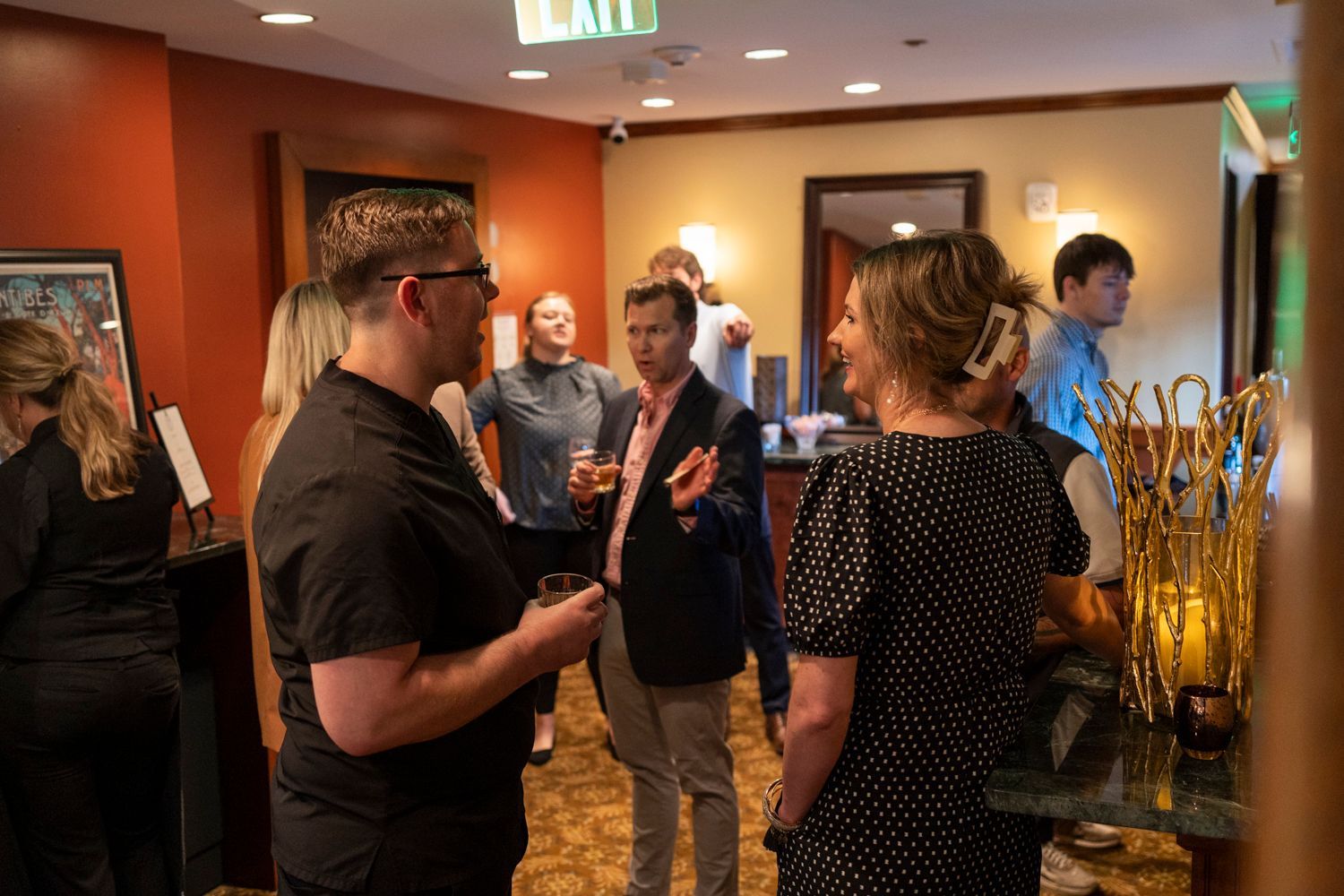 A group of people are standing in a room talking to each other.
